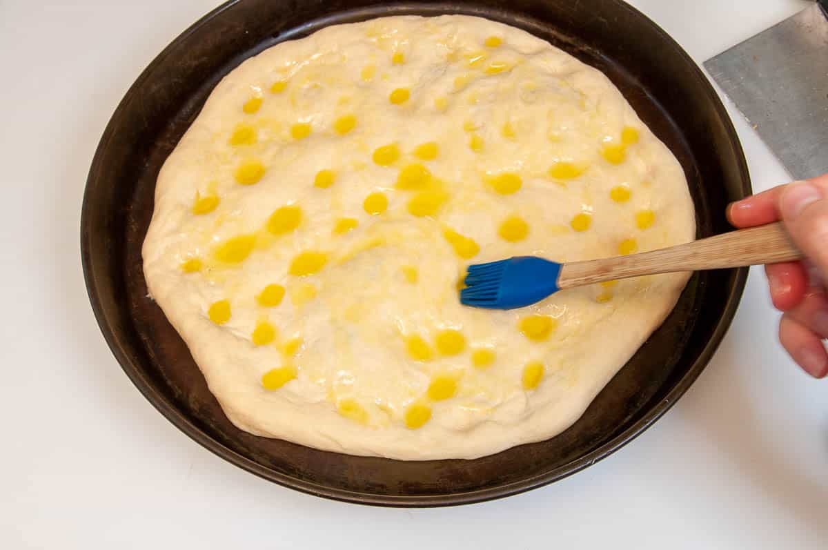 brushing the focaccia with olive oil