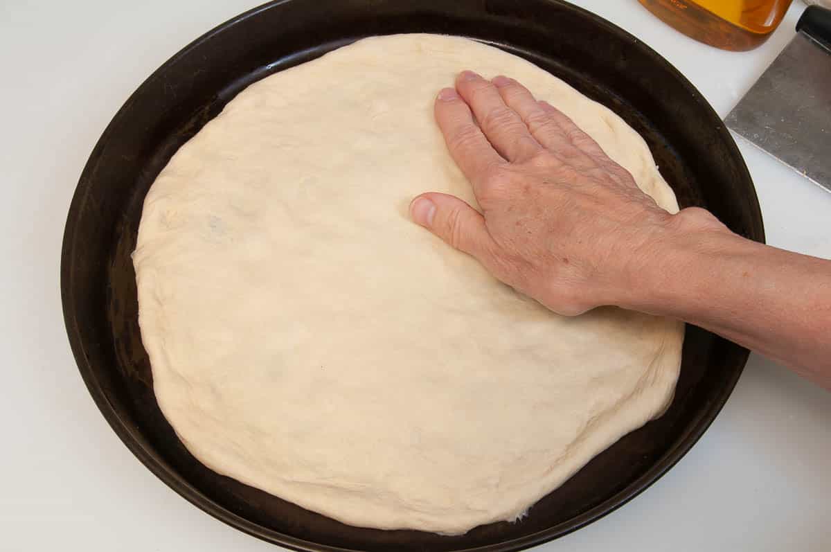 placing the dough onto a baking sheet or into a pizza pan.