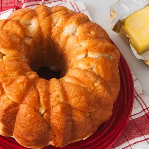uncut bread machine monkey bread on a plate with butter on the side.