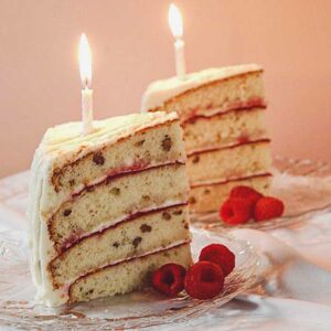 hickory nut cake slices with raspberry garnish and a candle on top of each slice.