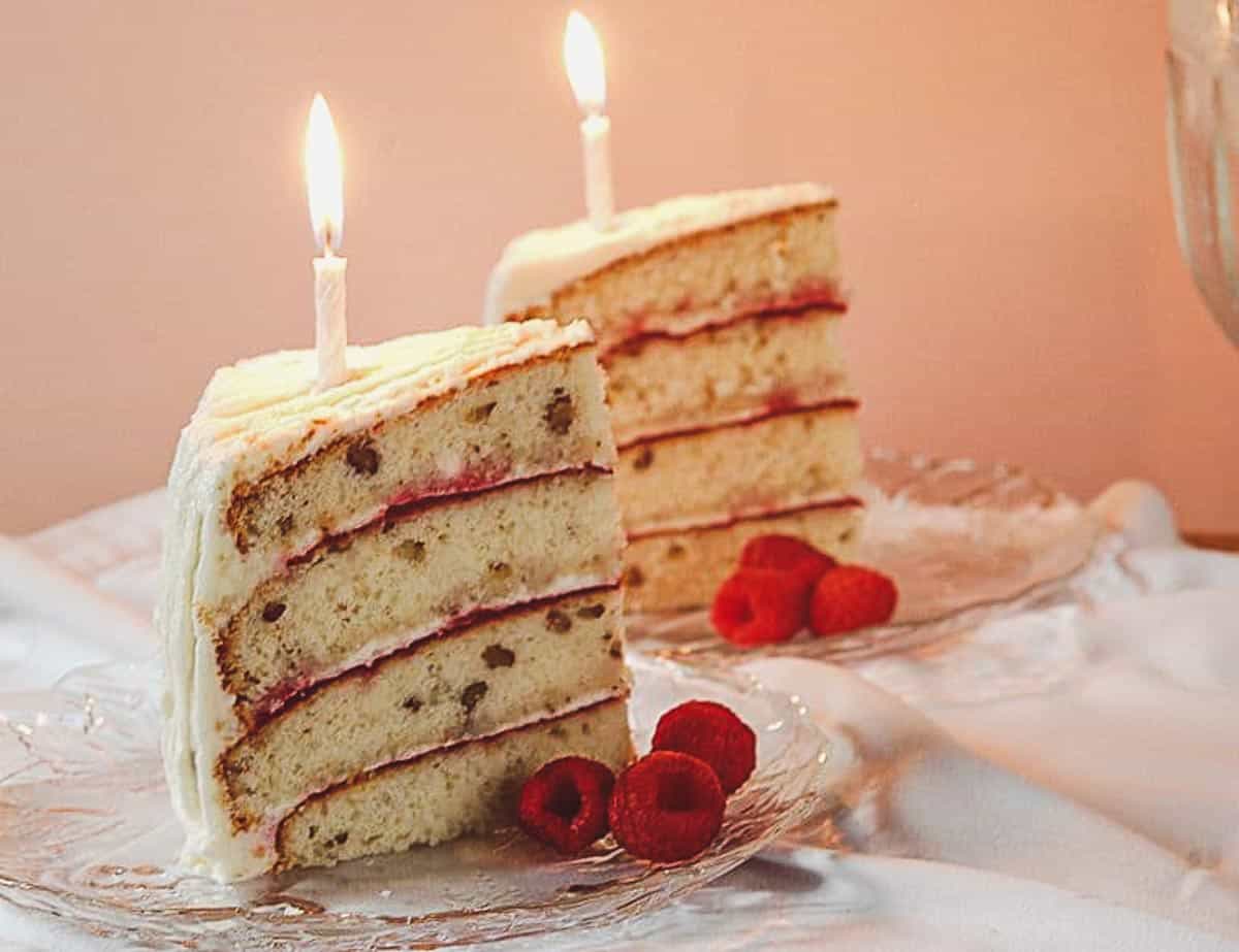 hickory nut cake slices with raspberry garnish and a candle on top of each slice.