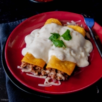 trwo green chile enchiladas on a red plate