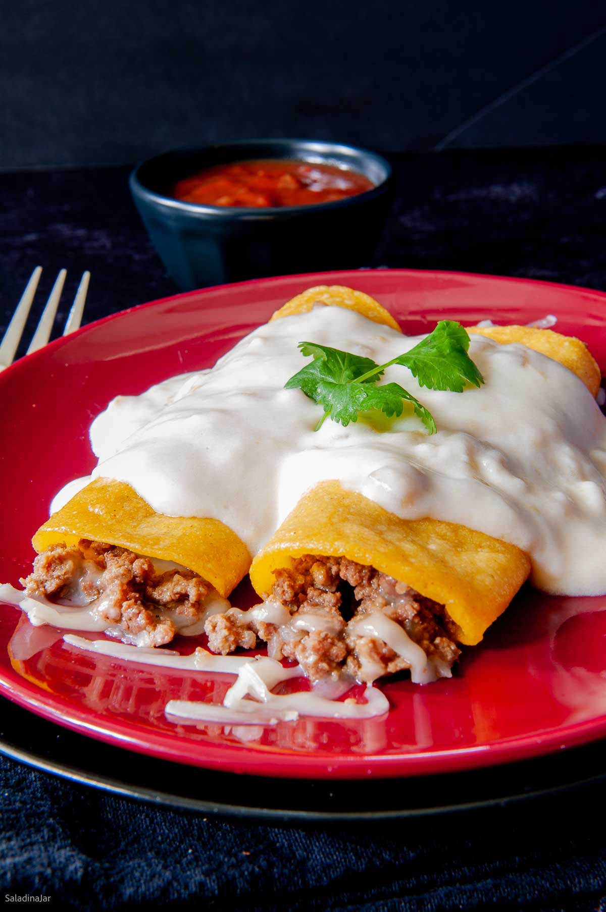 two green chile enchiladas on a plate ready to eat