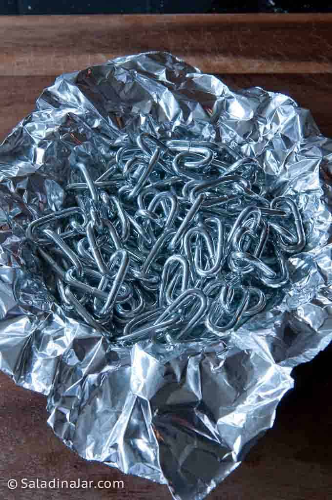 Using a chain to hold down crust during pre-bake