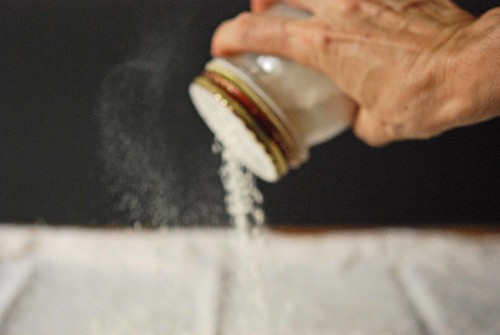 sprinkling flour over the pastry cloth