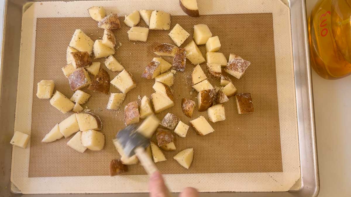 distributing potatoes on a prepared baking sheet