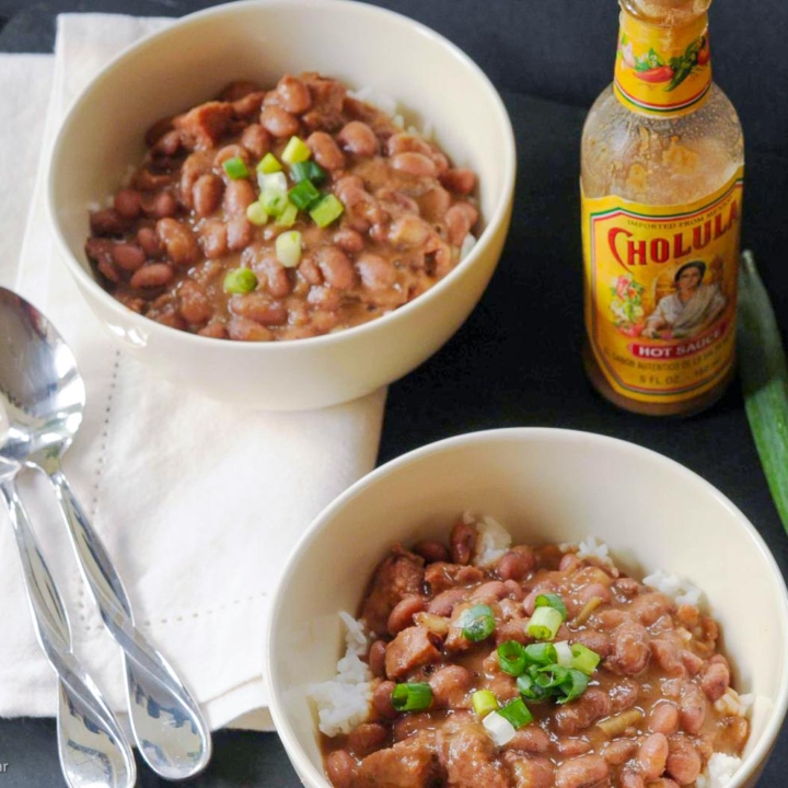 red beans and rice in two bowls with hot sauce