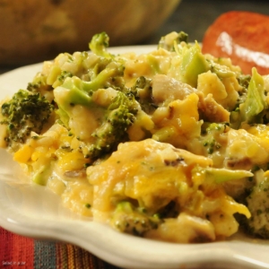 broccoli cheese casserole on a. plate with sausage on the side.