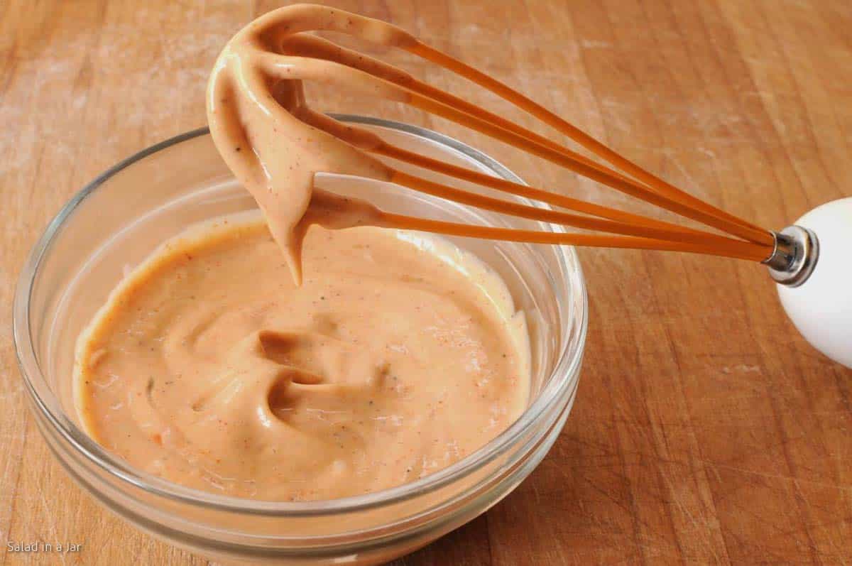 whisking cajun sauce in a small bowl.