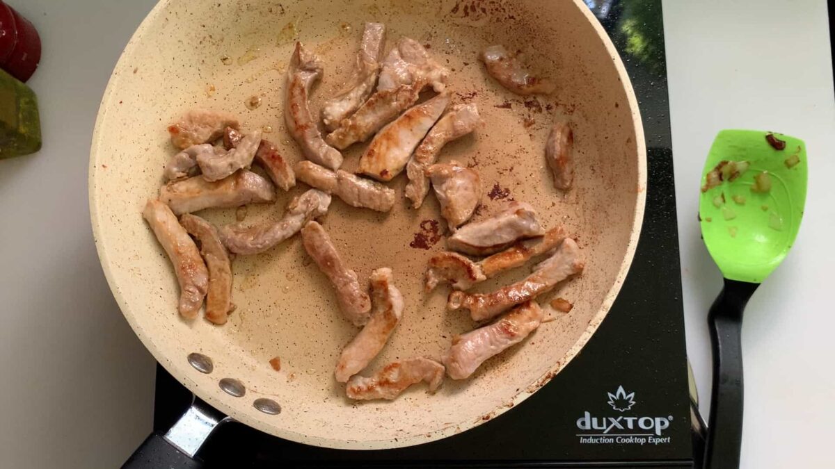 Browning pork strips in a skillet.