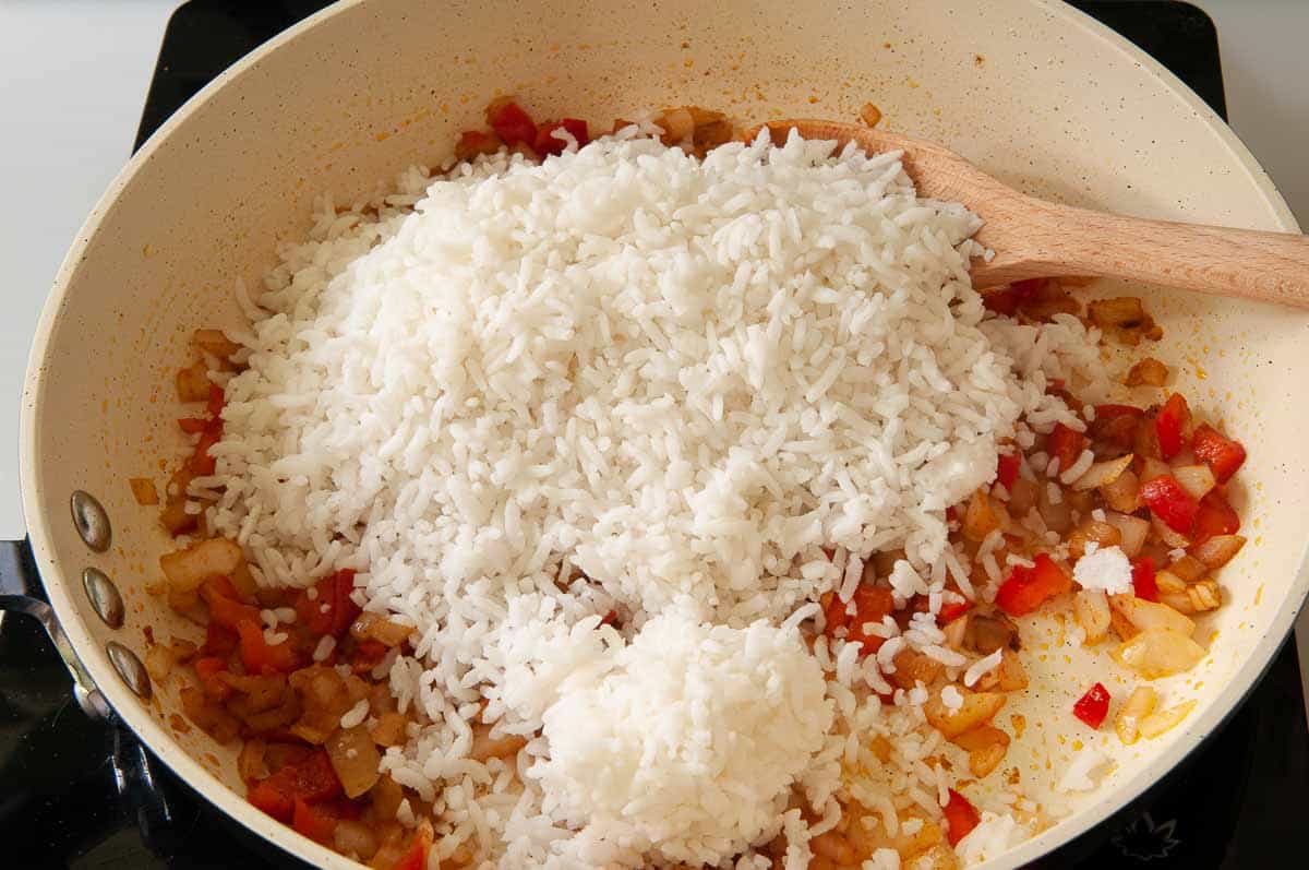 Adding cooked rice to skillet.