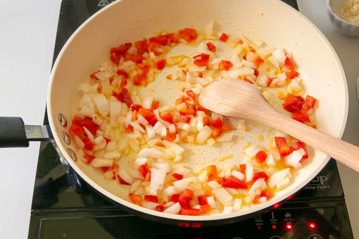 Adding onions and peppers to hot skillet