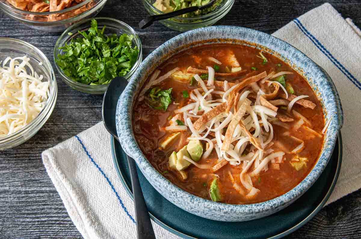 thick chicken tortilla soup surrounded by condiments