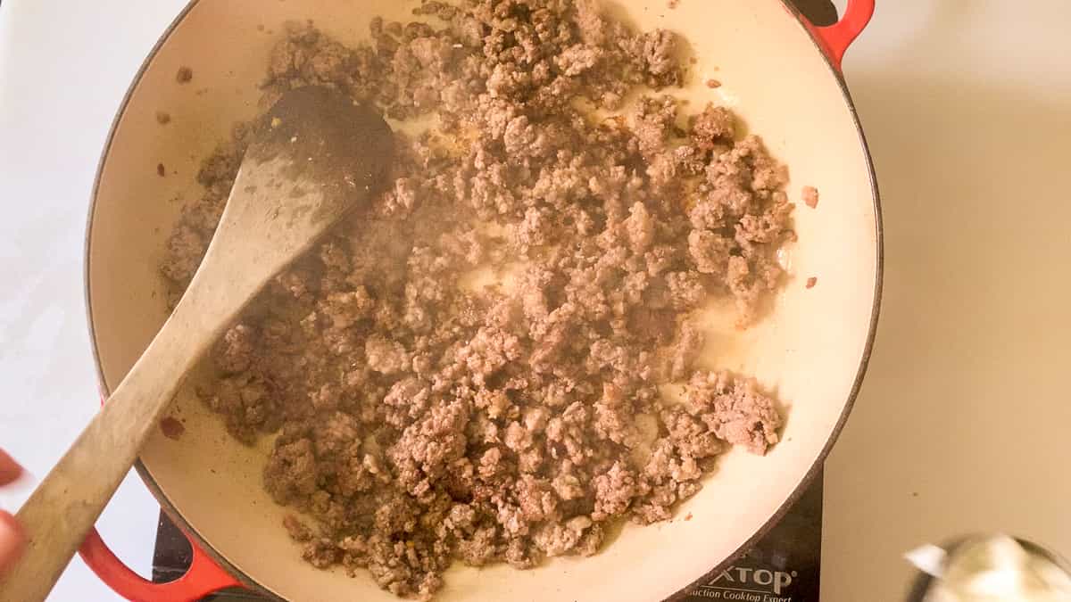 browning ground beef and sausage in a skillet.
