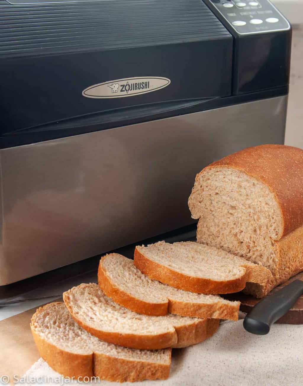 bread machine with sliced Honey Whole Wheat Bread sitting in front of it