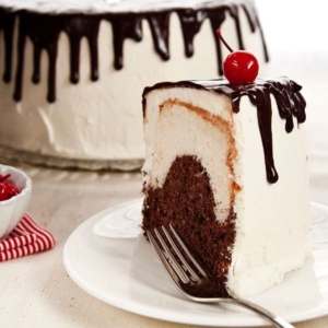 a slice of angel food cake with chocolate ganache with the whole cake in the background