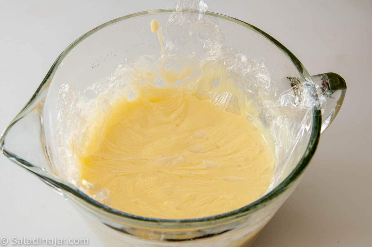 wrapping bowl with plastic wrap pushed down on the surface of the pudding.