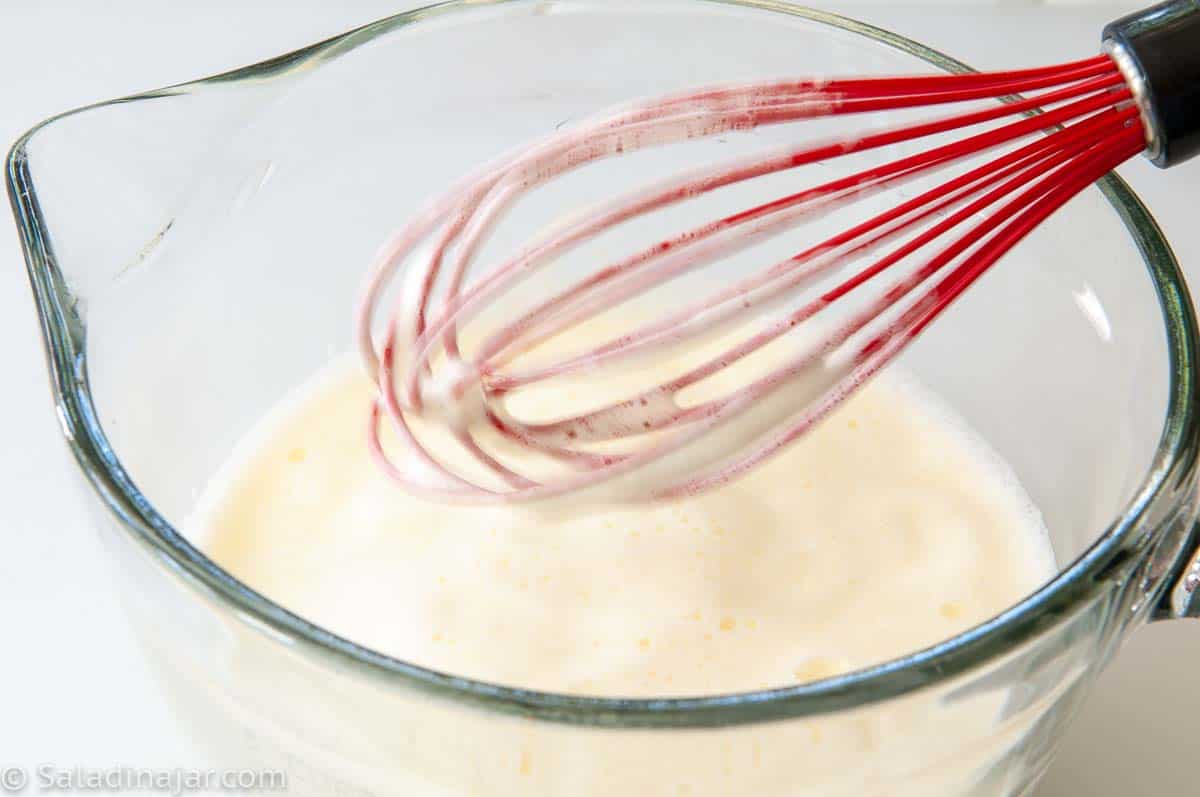 Using a whisk to stir custard while cooking in a microwave