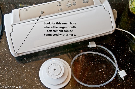 a countertop vacuum sealer showing where the hose inserts into the machine and the attachment.