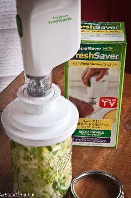 Using A Handheld Device To Vacuum Pack Lettuce Salad In A Jar