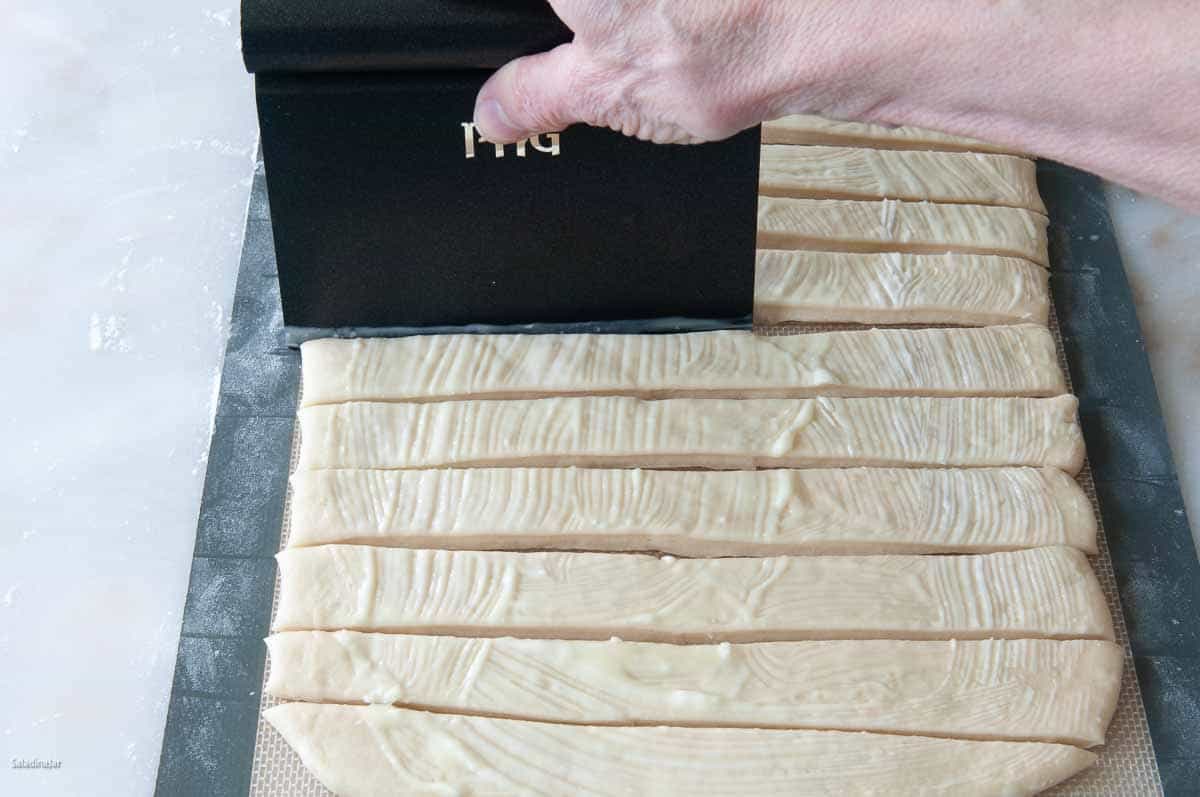 Cutting strips with a dough scraper.