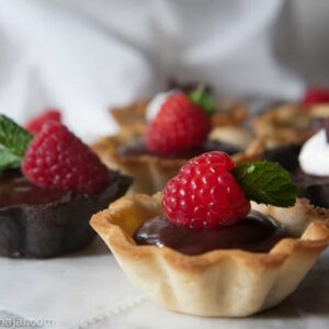chocolate ganache mini tarts garnished with raspberries an mint