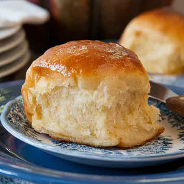 sweet potato bread machine roll on a plate with a honey butter glaze.