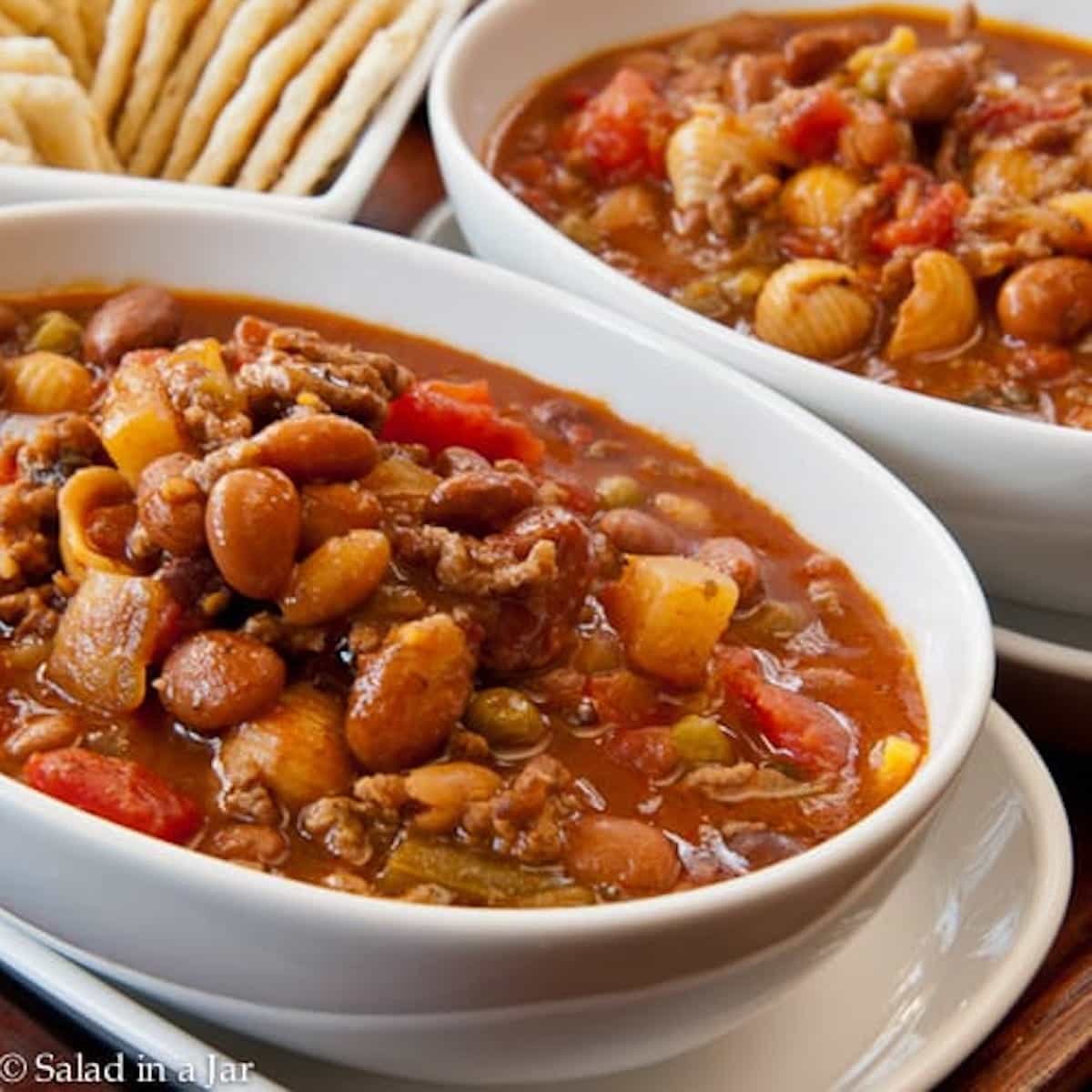 hamburger minestrone soup in bowls with saltines on the side.