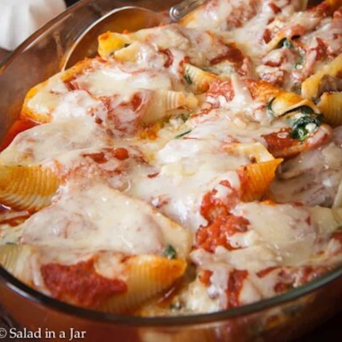 cheesy spinach and mushroom stuffed shells in a serving dish ready to eat.