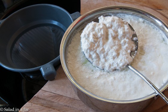 Removing curds with a slotted spoon.