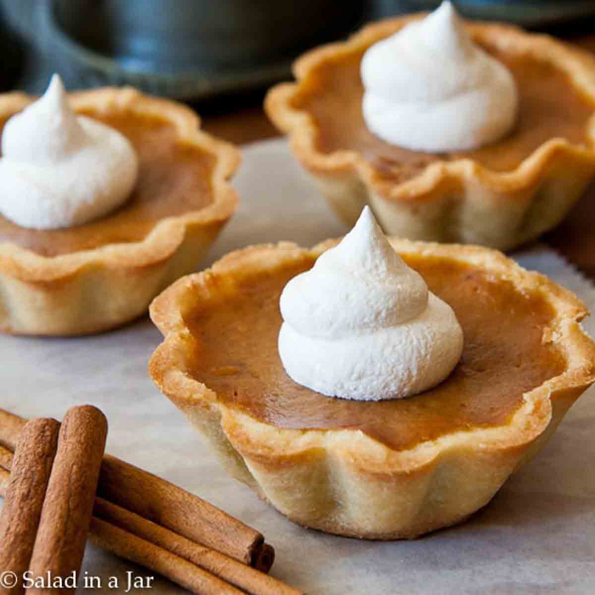 Ready to eat pumpkin mini-tarts with a shortbread crust and whipped cream on top.