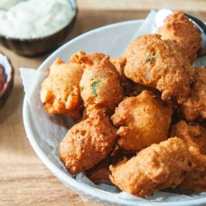 fried jalapeno hushpuppies on a platter with dipping sauces on the side