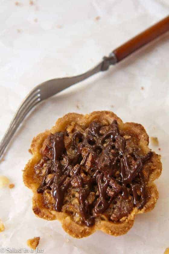 Chocolate pecan tartlets on a plate with a fork on the side.