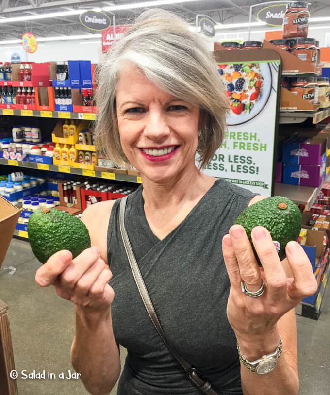 woman selecting avocados at the grocery store