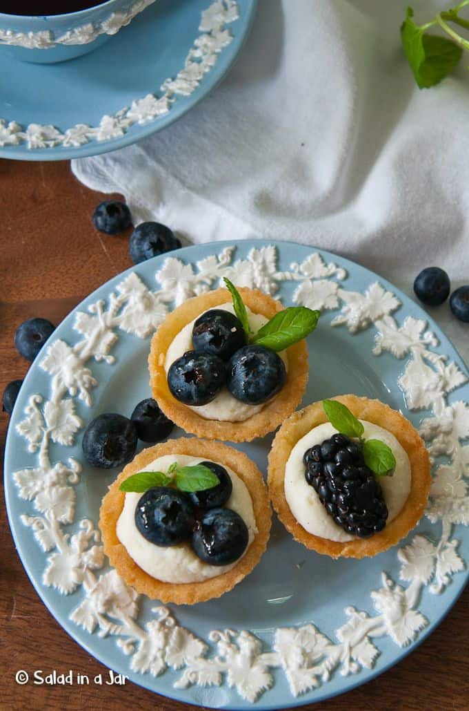 three small tarts decorated with blueberries, blackberries and mint