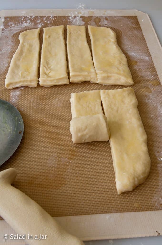 rolling up the butter-coated strips.