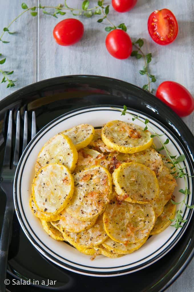 Roasted Parmesan Squash- on a plate garnished with fresh basil and cherry tomatoes on the side