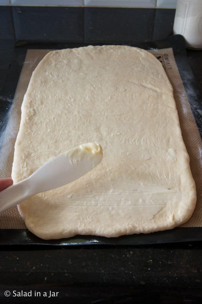 Applying butter to dough rectangle.