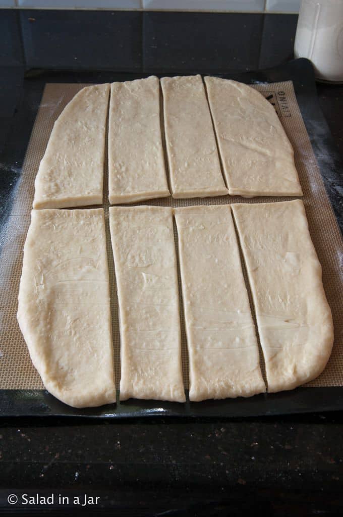 dough rolled out and sized with a pizza cutter in preparation for shaping.