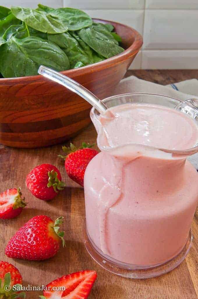 Strawberry Yogurt Salad Dressing sitting beside spinach salad and strawberries