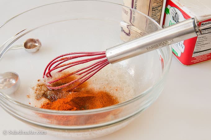 using a whisk to mix the egg white dipping mixture in a bowl.