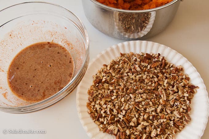 preparing the pecans to coat Sweet Potato Balls with egg whites in one bowl, and pecans on a paper plate.