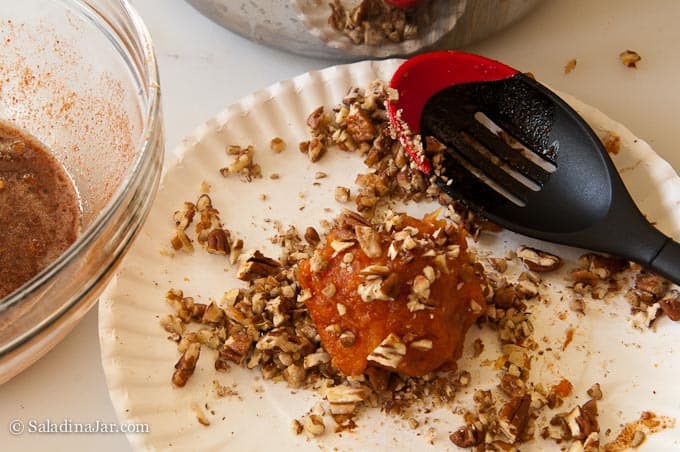 covering the Sweet Potato Balls with nuts using a spoon.