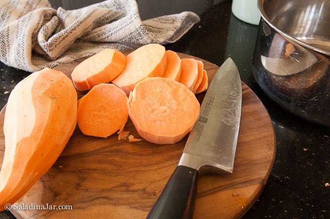 slicing raw potatoes with a kinfe on a chopping board