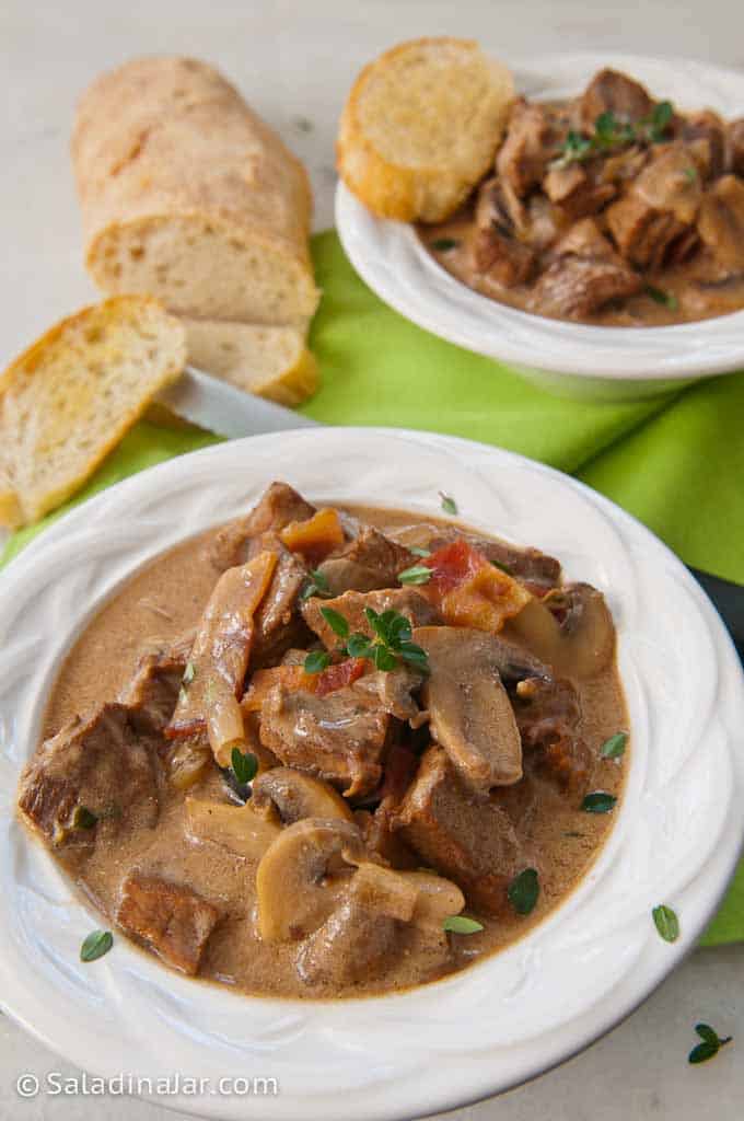 Zuppa di bistecca avanzata In in una ciotola con pane francese sul lato.