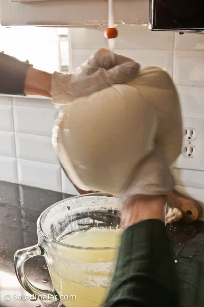 manually squeezing yogurt pouch to hasten straining process