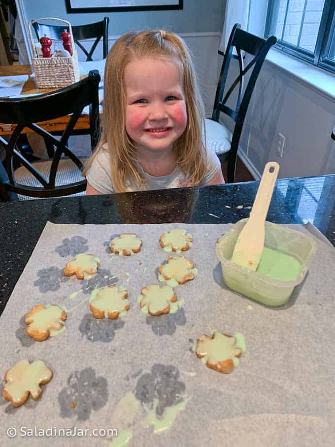 Frosting Shamrock Shortbread Cookies with granddaughter