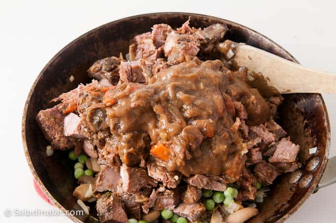 adding gravy to leftover beef roast and veggie mixture