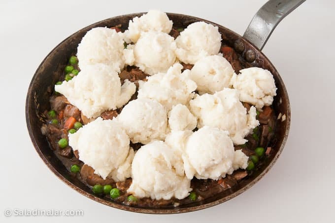 Distributing mashed potato topping over meat layer of Shepherd's pie