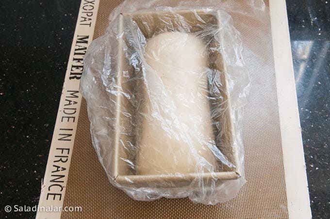 pan holding shaped dough covered with a cheap shower cap